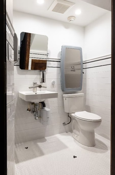A white subway-tiled bathroom with a dark banded border