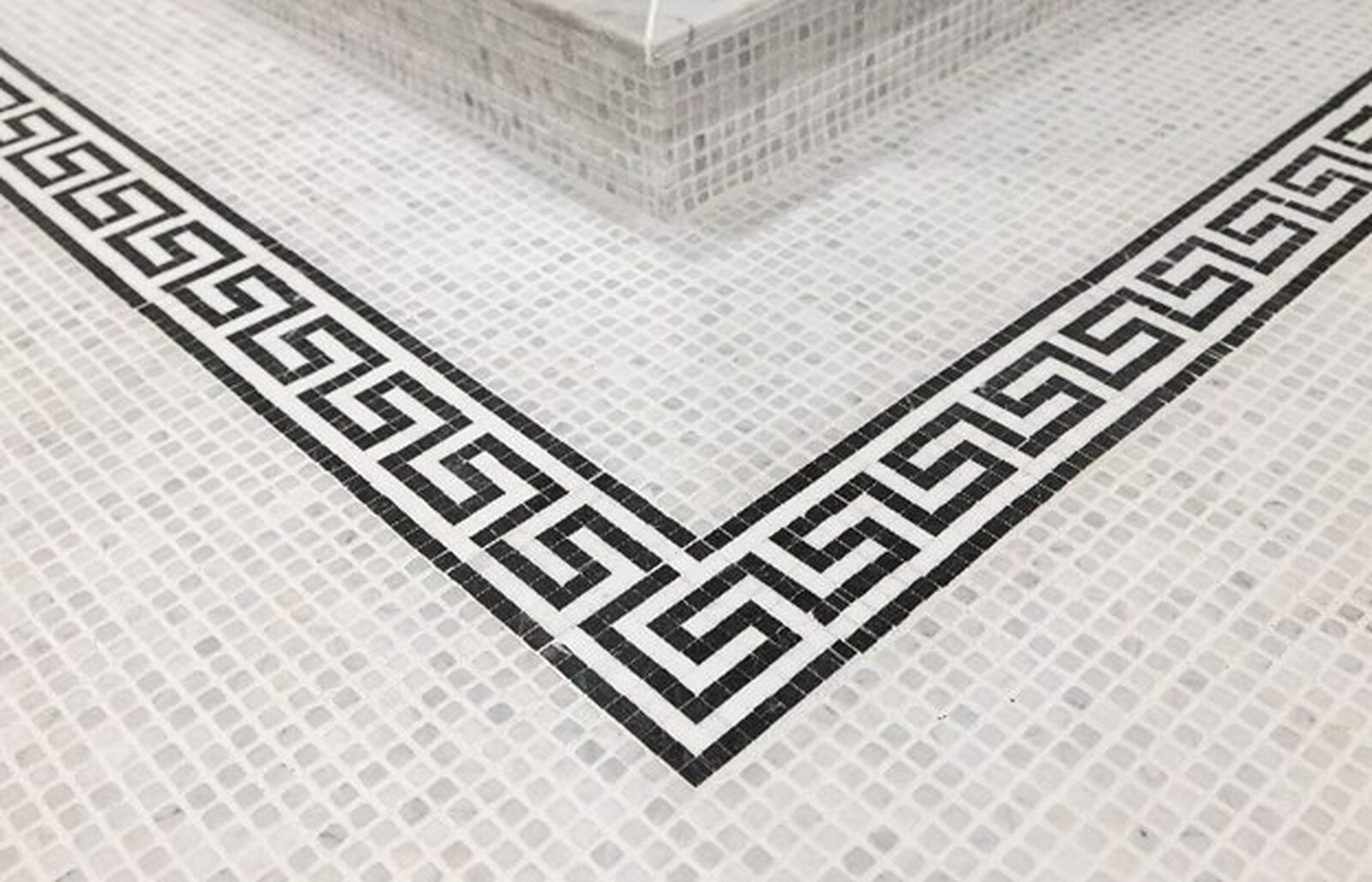A marble mosaic floor with a black Greek-key border set into the field