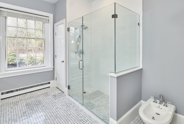 A glass shower enclosure beside a marble mosaic bathroom floor