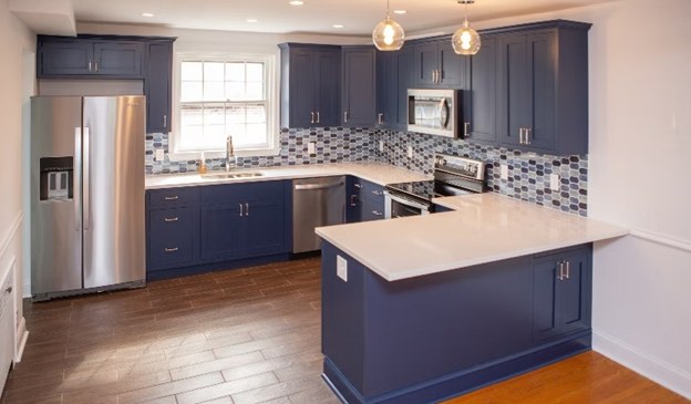 A renovated kitchen with wood-look plank flooring and a glass mosaic backsplash