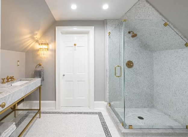 A carrara marble shower with brass fittings and a mosaic floor inset